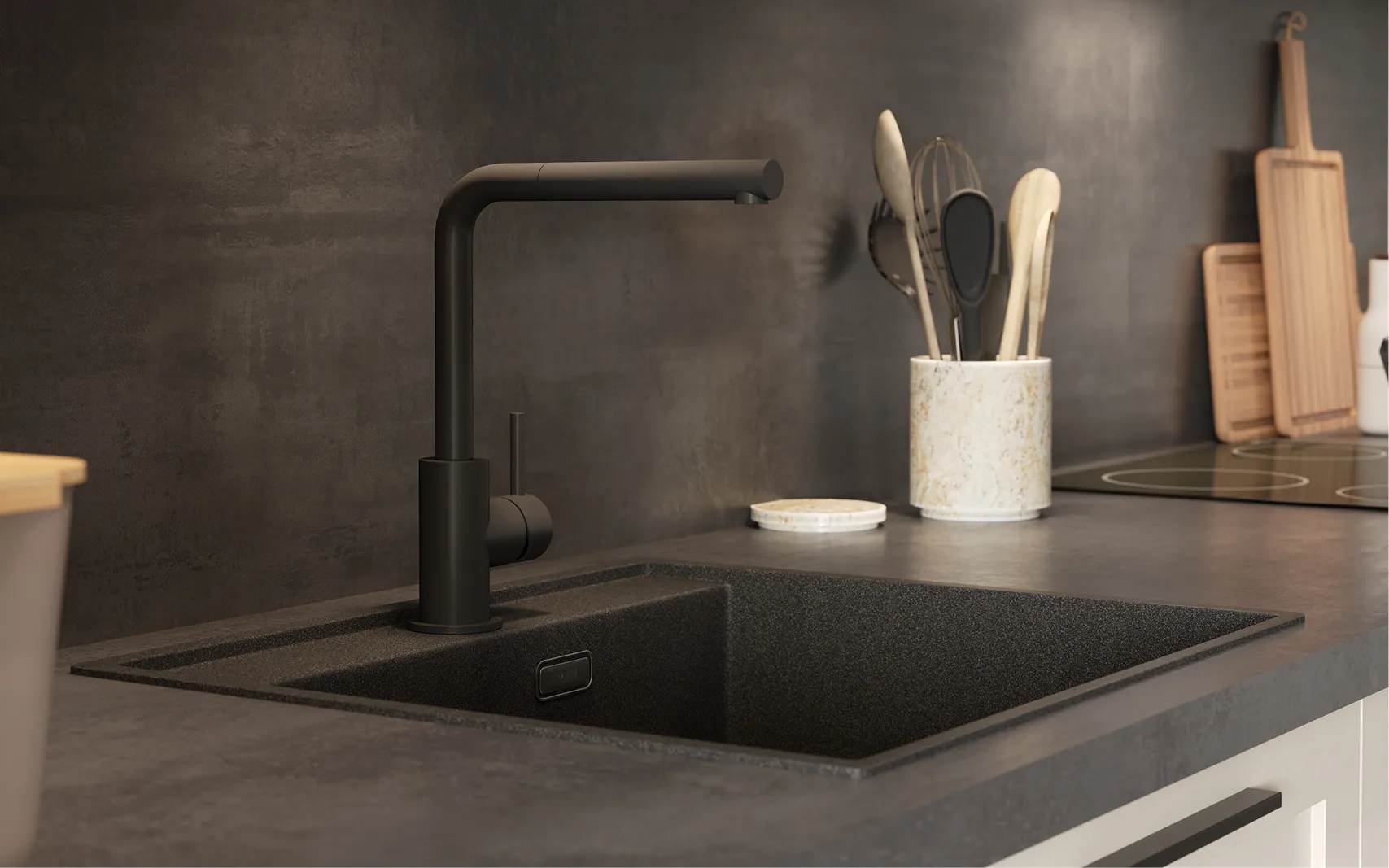 Nahaufnahme einer modernen Küchenarmatur in mattschwarz mit passender Spüle aus Granitverbund. Die dunkle Arbeitsplatte und Rückwand in Betonoptik schaffen einen eleganten Kontrast zu den hellen Fronten der Küche. 